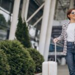 giovane-donna-con-bagagli-in-aeroporto-che-viaggia-e-parla-al-telefono-min