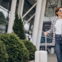 giovane-donna-con-bagagli-in-aeroporto-che-viaggia-e-parla-al-telefono-min